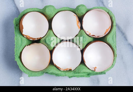 Studio shot of cracked, empty chicken egg shells in an egg box on a marble background - John Gollop Stock Photo