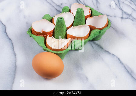 Studio shot of cracked, empty chicken egg shells in an egg box on a marble background - John Gollop Stock Photo