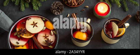 Mulled Wine for Christmas and winter holidays. Hot mulled wine drink with fruits and spices on black background, top view, banner. Stock Photo