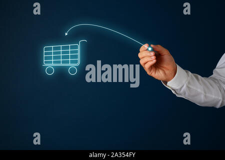 Online shopping concept - male hand drawing an arrow pointing in shopping cart on virtual interface with a gloving pen. Over navy blue background. Stock Photo