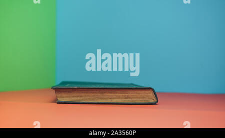 Book on a red table and green blue background. Stock Photo
