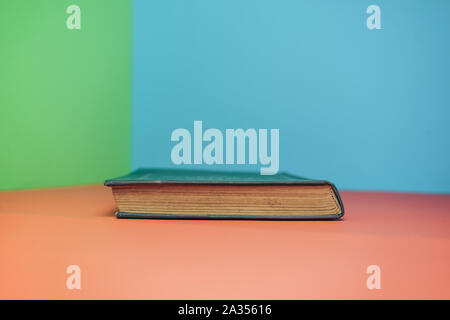 Book on a red table and green blue background. Stock Photo