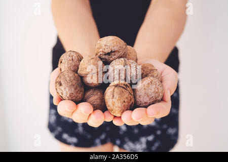 Detail of young woman's hands, holding a handful of organic walnuts. Selective focus Stock Photo