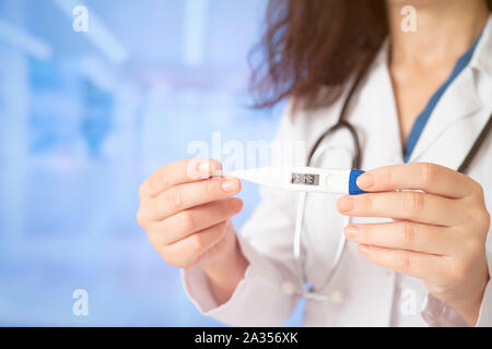 Young doctor woman holding thermometer Stock Photo