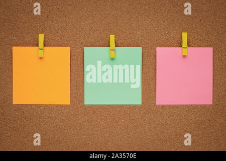 Blank notes on cork board, notice board. Blank stickers on clothespins on wood background. Copy space. Concept of planning. Colorful paper sticker, em Stock Photo