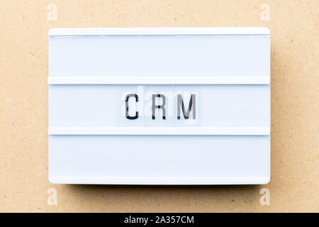 White lightbox with word CRM (Abbreviation of Customer Relationship Management) on wood background Stock Photo