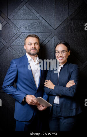 Happy young elegant businesswoman and her middle aged confident colleague Stock Photo