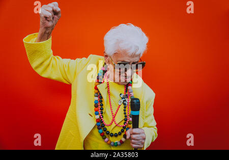 Funny grandmother portraits. Senior old woman dressing elegant for a special event. Rockstar granny on colored backgrounds Stock Photo