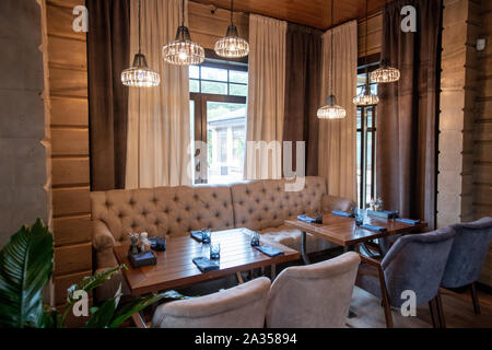 Beige leather sofa and soft velvet armchairs standing by wooden table in cafe Stock Photo