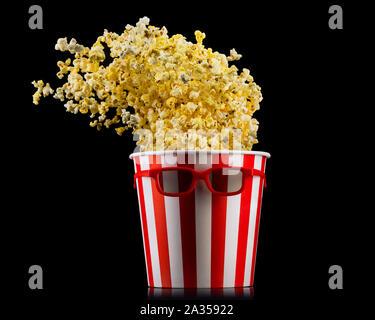 Flying popcorn from striped bucket isolated on black background Stock Photo