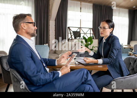 Young confident Asian businesswoman explaining her opinion to colleague Stock Photo