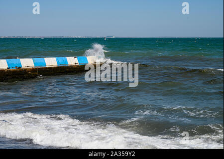 Black sea, Small waves break on the concrete breakwater. Sunny day cloudless sky Stock Photo