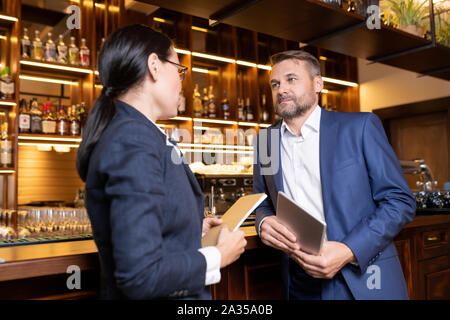 Two owners of luxurious restaurant interacting by bar counter Stock Photo