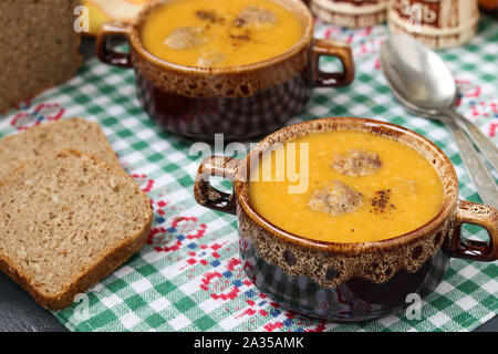 Pumpkin soup in bowls on checkered napkin on a dark background. Stock Photo