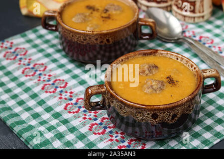 Pumpkin soup in bowls on checkered napkin on a dark background. Stock Photo