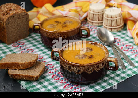 Pumpkin soup in bowls on checkered napkin on a dark background. Stock Photo