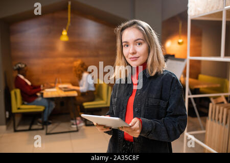 Pretty young successful student using touchpad while preparing homework Stock Photo