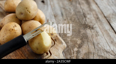 https://l450v.alamy.com/450v/2a35cwf/raw-potatoes-with-a-vegetable-peeler-close-up-2a35cwf.jpg