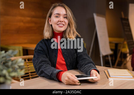 Happy young casual student with toothy smile using touchpad in college cafe Stock Photo