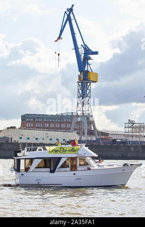 Hamburg, Germany. 05th Oct, 2019. During a protest action a boat drives with a banner with the inscription: 'Dove Elbe save' a parade before the landing bridges in the port of Hamburg. The demonstrators fear that the Dove Elbe at the Tatenberg lock could open towards the northern Elbe and thus become a tidal water with ebb and flow. Credit: Georg Wendt/dpa/Alamy Live News Stock Photo