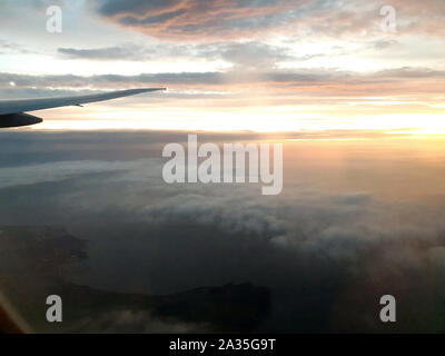 View from airplane window inside the clouds with colorful sunrise Stock Photo