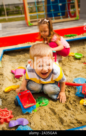 Crying unhappy boy play with car in sandbox Stock Photo