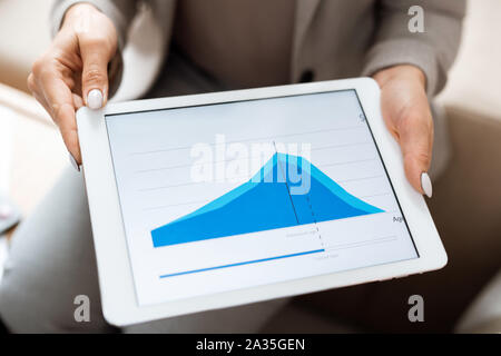 Hands of real estate agent holding tablet with blue financial graph on display Stock Photo