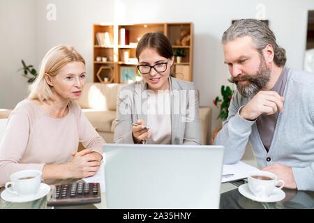 Mature couple looking at laptop display while financial advisor explaining data Stock Photo