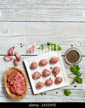 Raw  meatballs with vegetables and herbs on a table Stock Photo