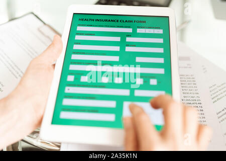 Healthy insurance claim application in electronic form on display of touchpad Stock Photo