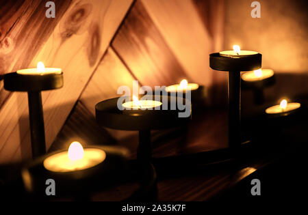 decoration and christmas concept - candles burning in lanterns on window sill and festive garland string at home Stock Photo