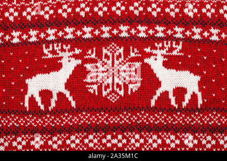 Close-up shot of red knitted elks and snowflake Scandinavian style ornament cristmas sweater background Stock Photo