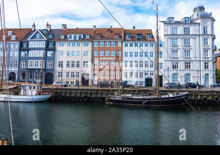 Copenhagen, Denmark - May 04, 2019: Colourful facades and restaurants on Nyhavn embankment and old ships along the Nyhavn Canal in Copenhagen, Denmark