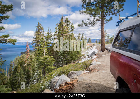 A red four by four truck parked on the side of an overlook of Emerald Bay in Lake Tahoe, California on a sunny day in early winter with snow and gree. Stock Photo