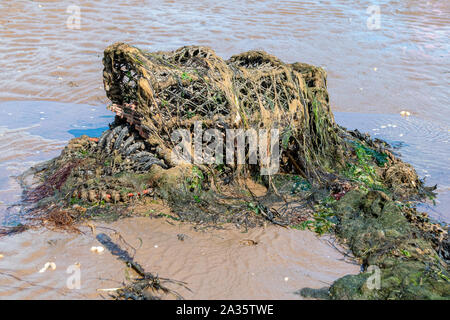 Marine pollution with discarded fishing net pots covered in seaweed and algae Stock Photo