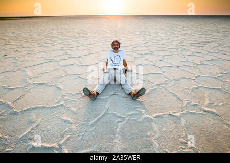 Man seated on a salt lake. Stock Photo