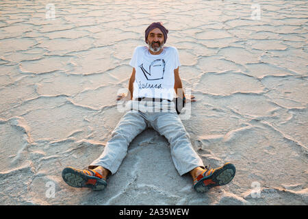 Man seated on a salt lake. Stock Photo
