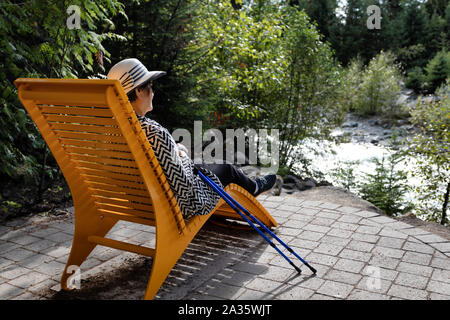 Portrait of senior woman relaxing outdoors in chair after hiking Stock Photo
