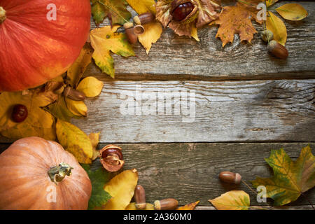 Thanksgiving autumn background on dark wooden surface, pumpkins, withered leaves, acorns and chestnuts, selective focus Stock Photo