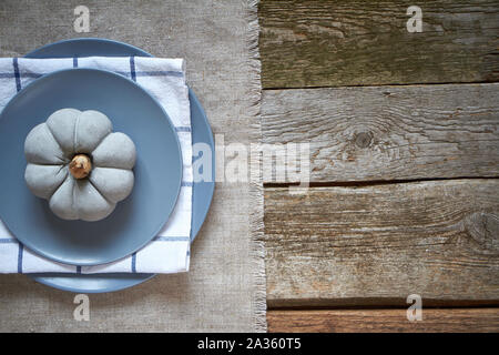 Thanksgiving table setting, cement pumpkin on gray plate on a dark wooden surface Stock Photo