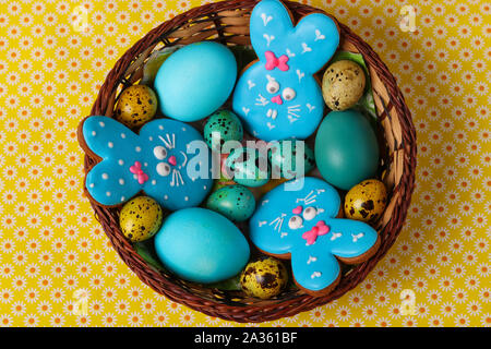 Easter gingerbreads Rabbits , Yellow and blue chicken and quail eggs in a wicker basket, Top view Stock Photo