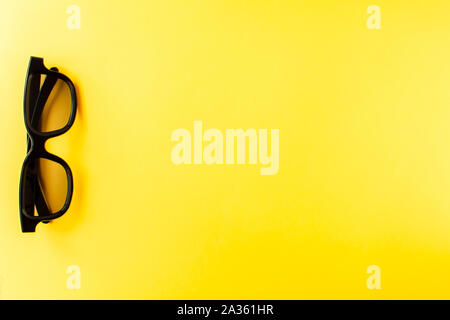 View from above of pair 3D black glass on yellow background. Flat lay, cinema concept Stock Photo