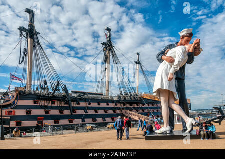 Embracing Peace, also known as Unconditional Surrender by Seward Johnson at Portsmouth Historic Dockyard with HMS Victory in background. Stock Photo