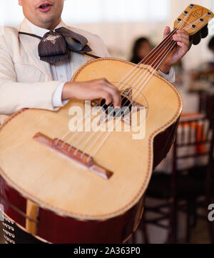 photo of mariachi man wearing traditional outfit and holding guitar instrument Stock Photo