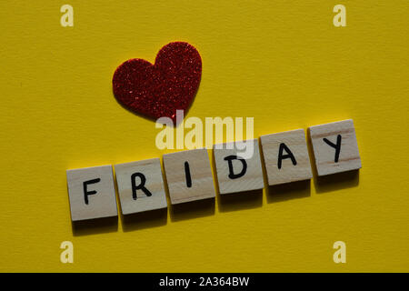 Friday in wooden alphabet letters on a bright yellow background with a red glitter heart Stock Photo