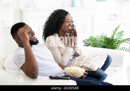 Young black family couple watching comedy movie on tv Stock Photo