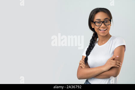 Excited student girl in eyeglasses posing over grey background Stock Photo