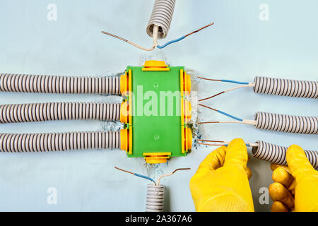 Electric services, electrician connects the electrical conduit to a rectangular plastic distribution box. Electrical work, installation of electrical Stock Photo