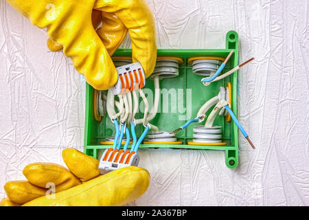Electrical installation work, junction box mounting. Use of splicing conductor connector type of push lever terminal. Electrical household services. E Stock Photo