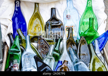 Many coloured, compressed, flat bottles from glass, laying on the ground Stock Photo